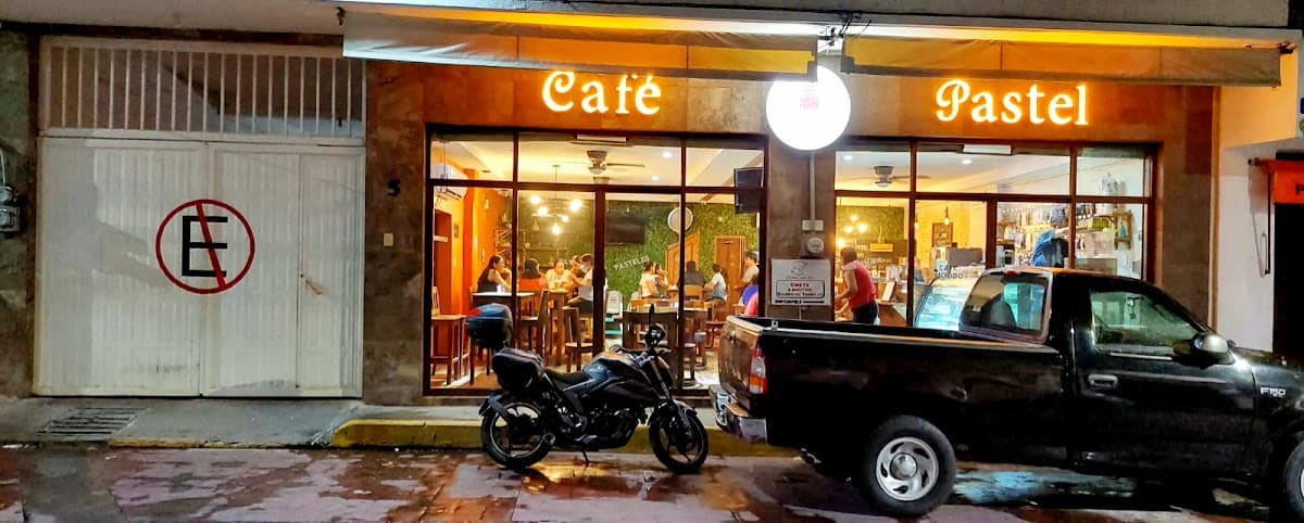 Exterior de Cafetería y pastelería PA‑TÍ con su letrero colorido y una vitrina llena de pasteles y café