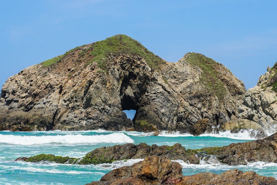Majestic rock formation with ocean waves at Zipolite Beach, Oaxaca, Mexico, perfect coastal scenery.