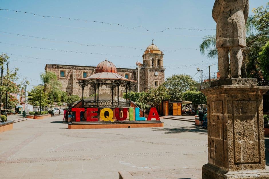 Vibrant Tequila sign in sunny Mexican plaza with historic architecture.