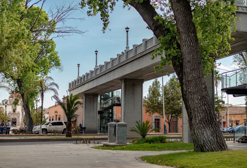 Scenic view of an urban footbridge surrounded by trees and buildings in Durango, Mexico.