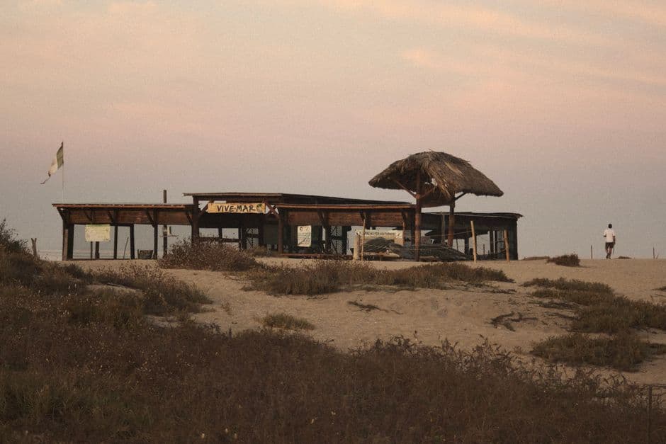 A serene shot of a rustic beach hut and surrounding dunes at dusk in Puerto Escondido, Mexico.