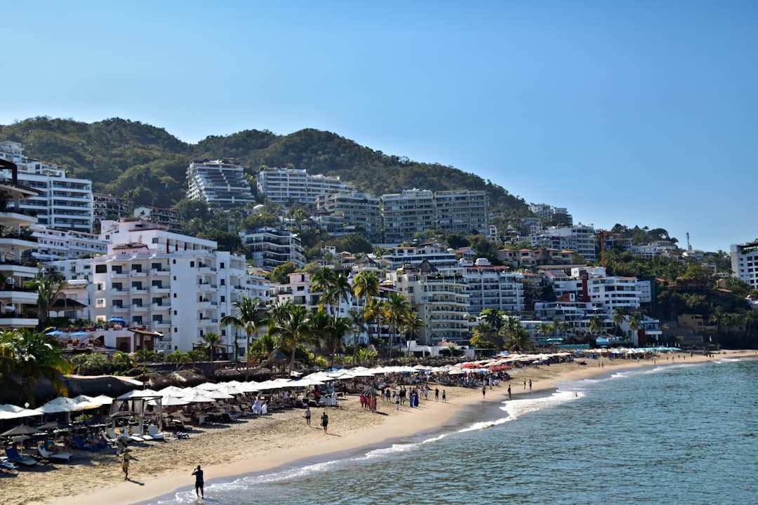 Beachfront buildings line a sunny coast.