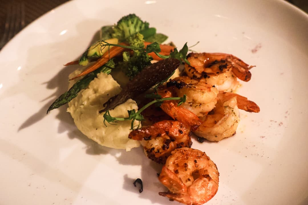 Grilled shrimp with sides on a white plate.
