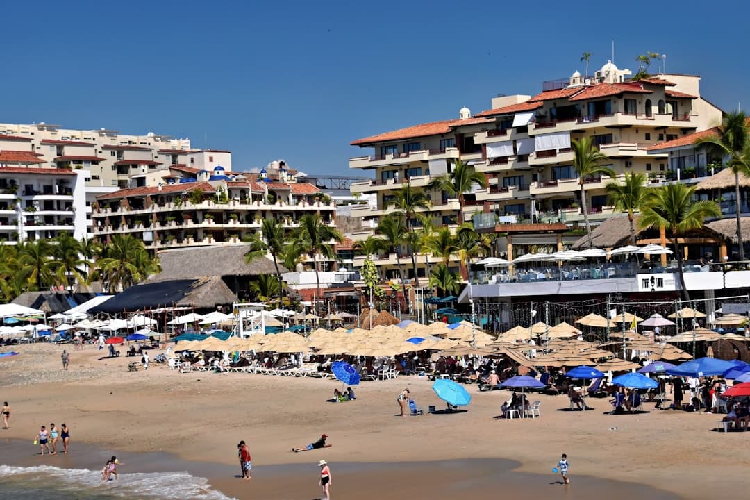 Beach with many umbrellas and buildings in the background.