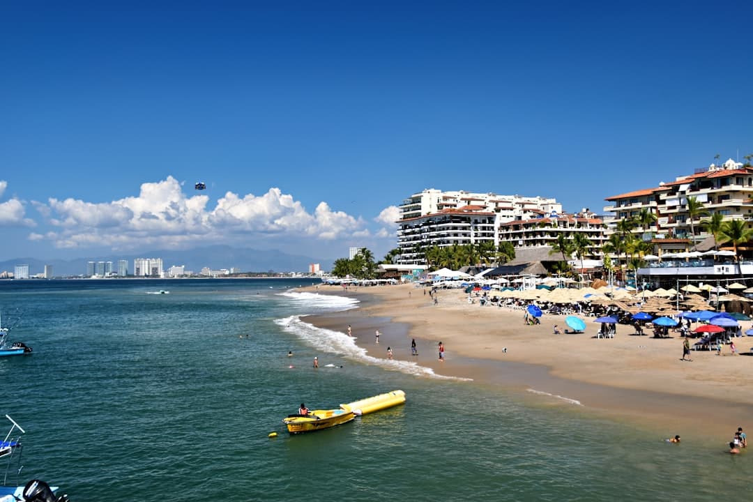 Sunny beach with resort buildings and ocean waves.