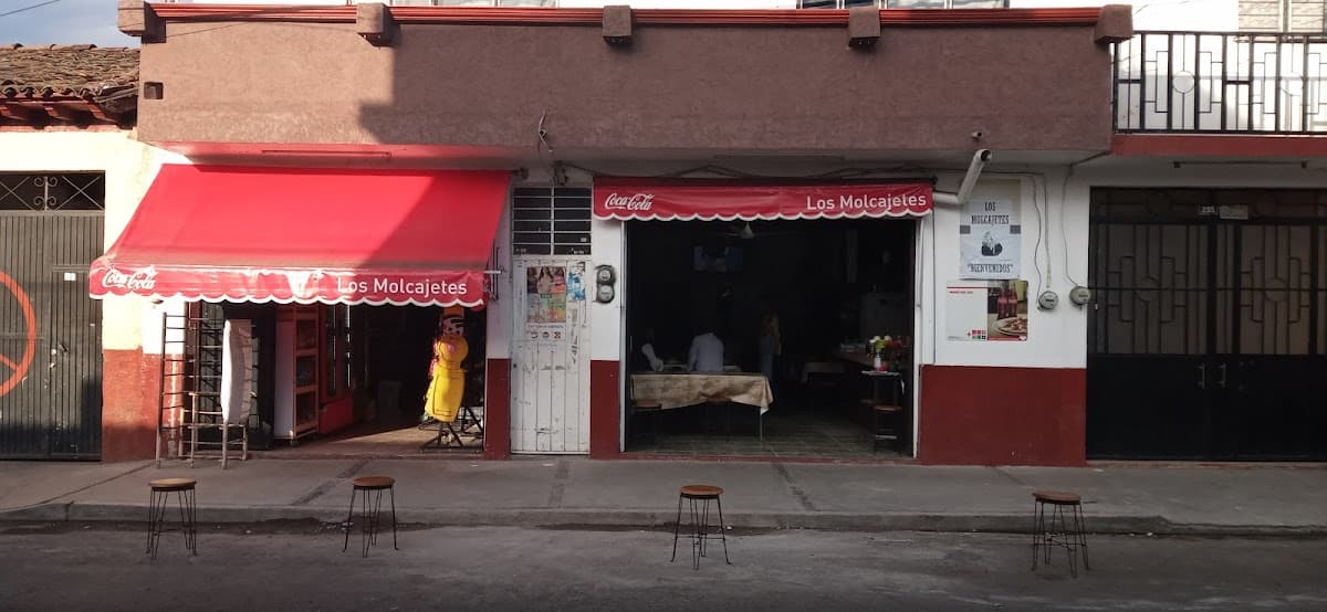Exterior iluminado de Roma Pizza Wings and Beer Quiroga con letrero y mesas al aire libre, mostrando una bandeja de alitas crujientes