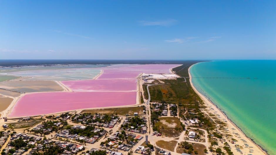 Stunning aerial view of vibrant pink salt ponds and turquoise sea in colorful Mexican landscape.