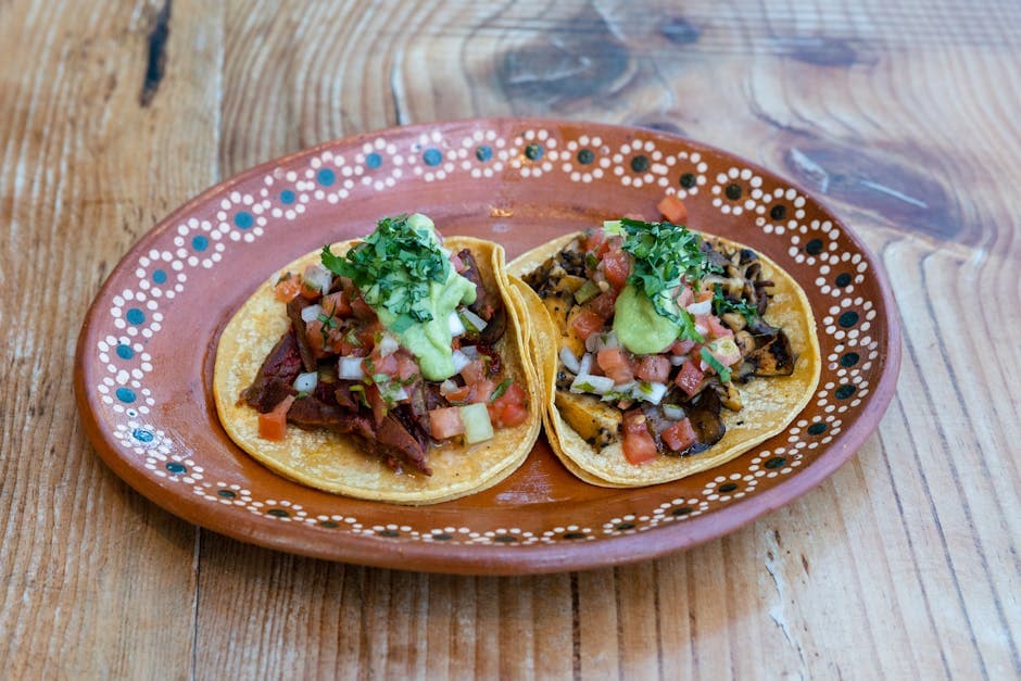 Close-up of two Mexican tacos with salsa and cilantro on a traditional painted plate.