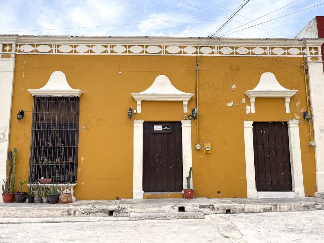 Colonial yellow building with dark wooden entrances and decorative trim.