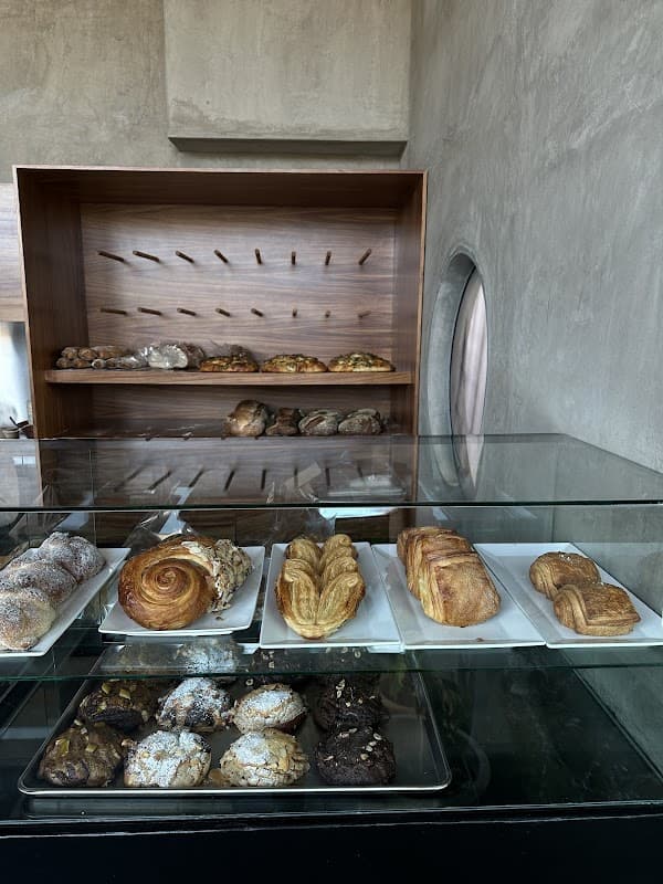 Fachada de Conxa panadería en Cañada Real 165, con vitrinas de panes y la barra de horchata latte al frente, clientes entrando