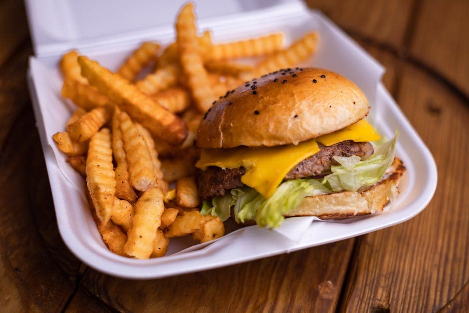 Mouth-watering cheeseburger with crinkle-cut fries in a takeout box, perfect for lunch or a quick meal.