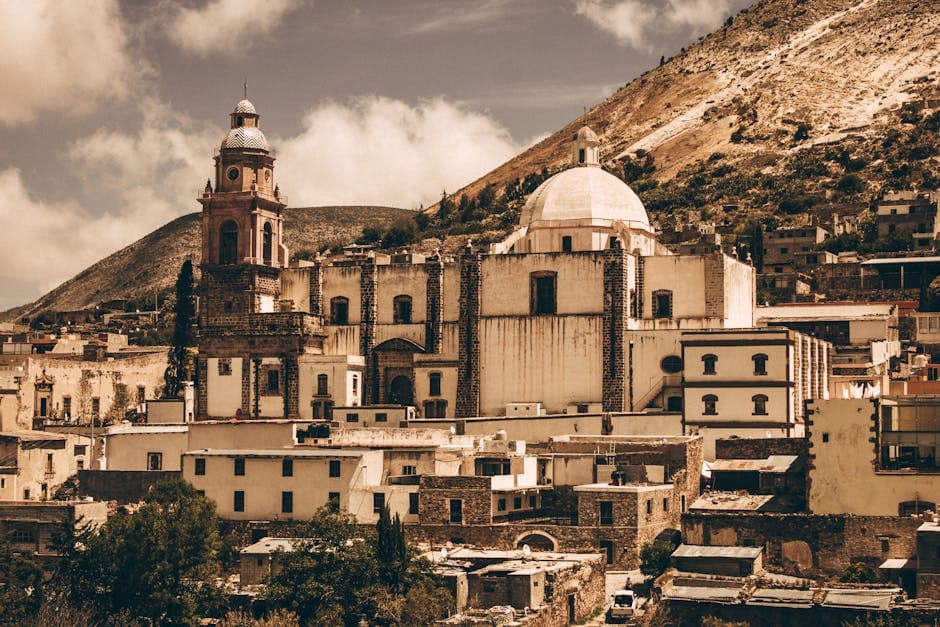 Explore the stunning colonial architecture of a Mexican town with its iconic domed church and scenic mountain backdrop.