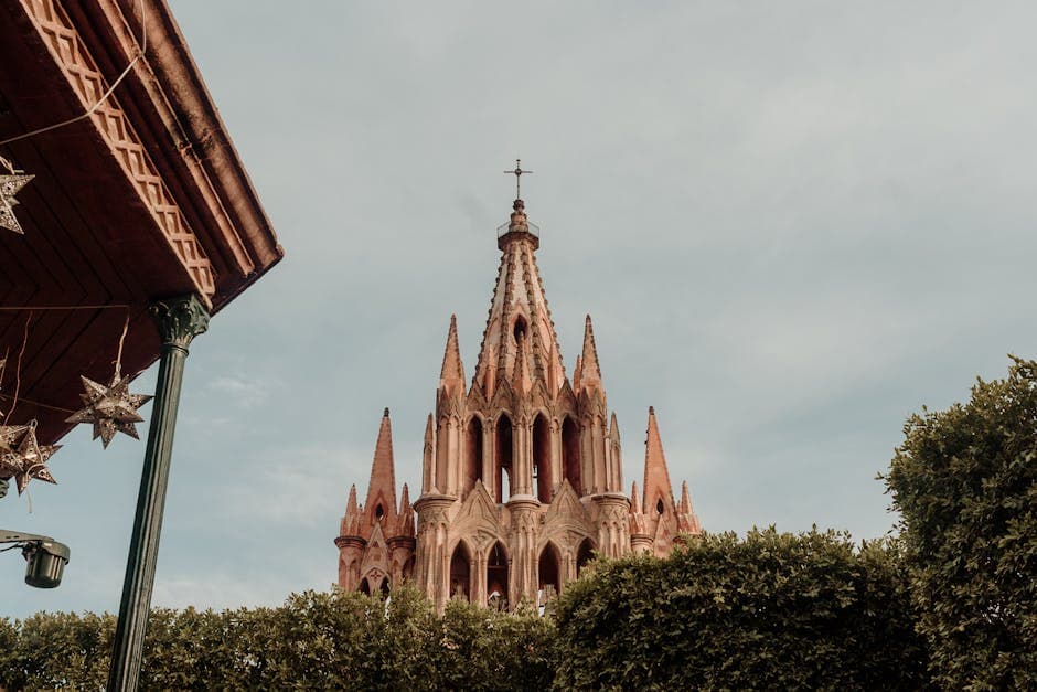 A beautiful view of the Parroquia de San Miguel Arcángel in San Miguel de Allende, framed by greenery.