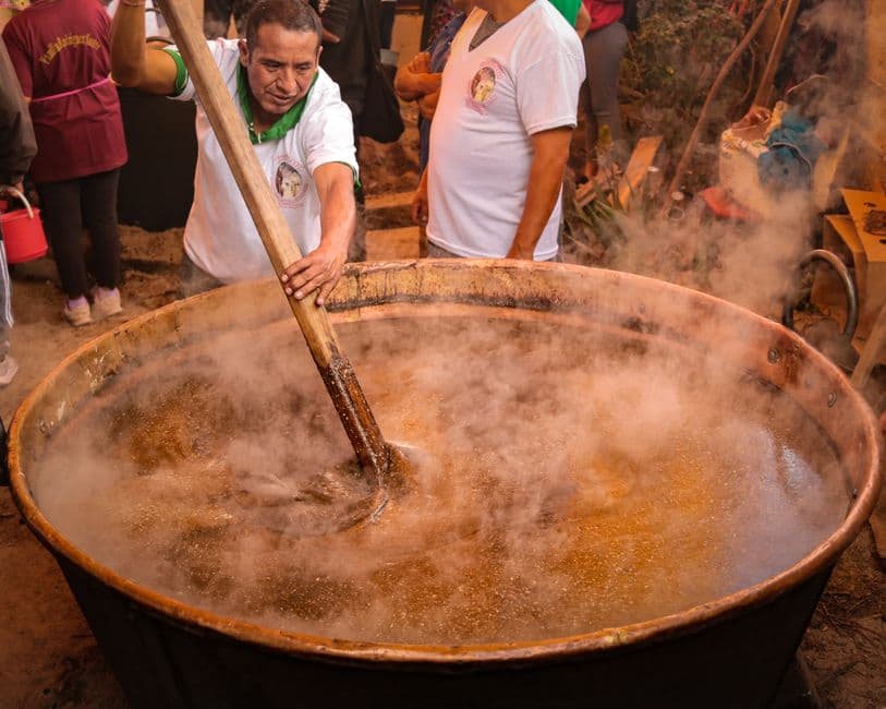Man stirring a large pot of traditional Mexican soup, showcasing cultural cooking methods.