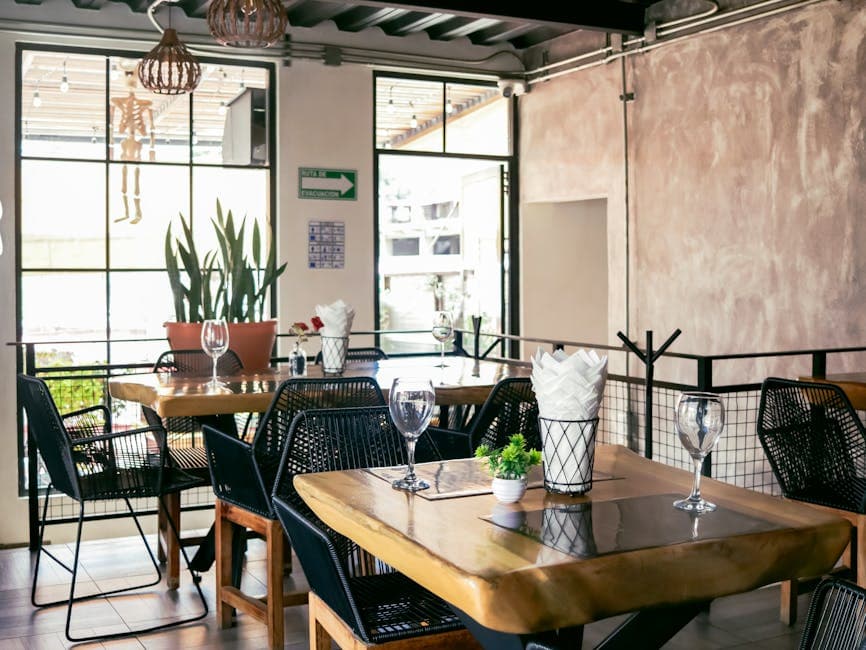Sunlit modern restaurant interior with wooden tables and chic decor, perfect for a warm dining experience.