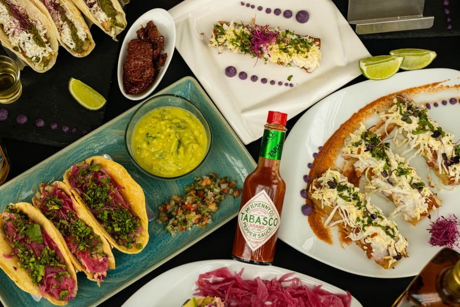 Colorful Mexican taco spread with Tabasco sauce highlights delicious flavors.
