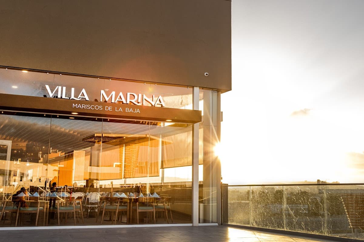Vista exterior de Villa Marina Península con su señal luminosa y mesas al aire libre