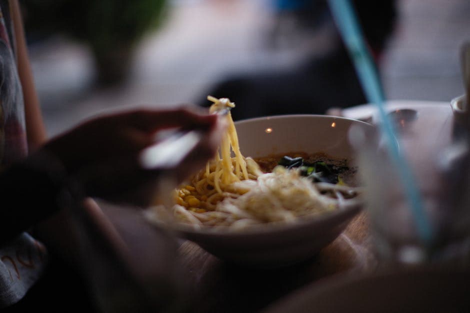 Close-up of a bowl of freshly served Asian noodle soup with chopsticks.