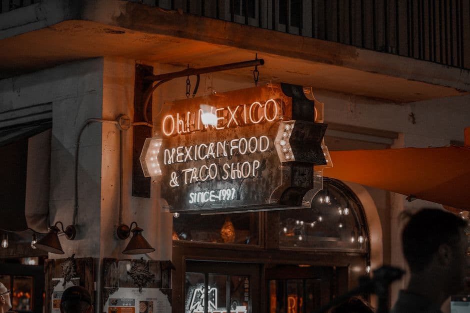 Illuminated neon sign of Oh! Mexico Mexican Food & Taco Shop at night in an urban setting.