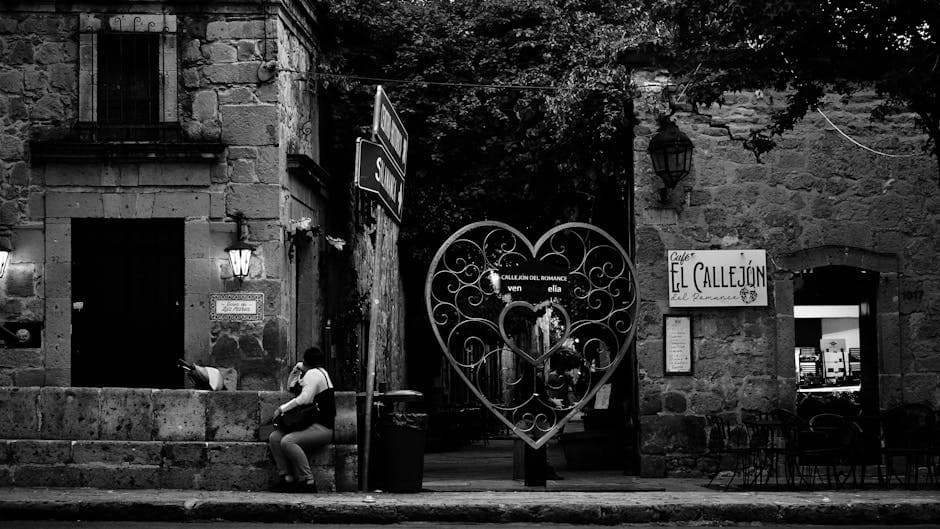 Black and white view of Callejón del Romance in Morelia with heart-shaped gate and street scene.