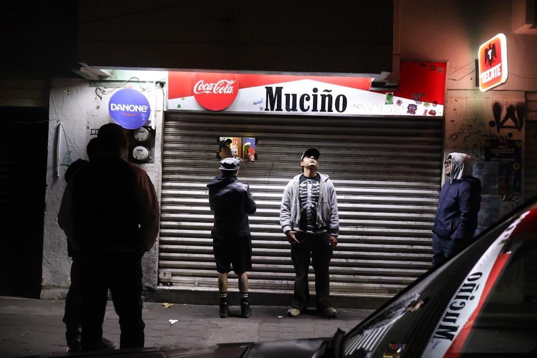People stand outside a closed store at night.