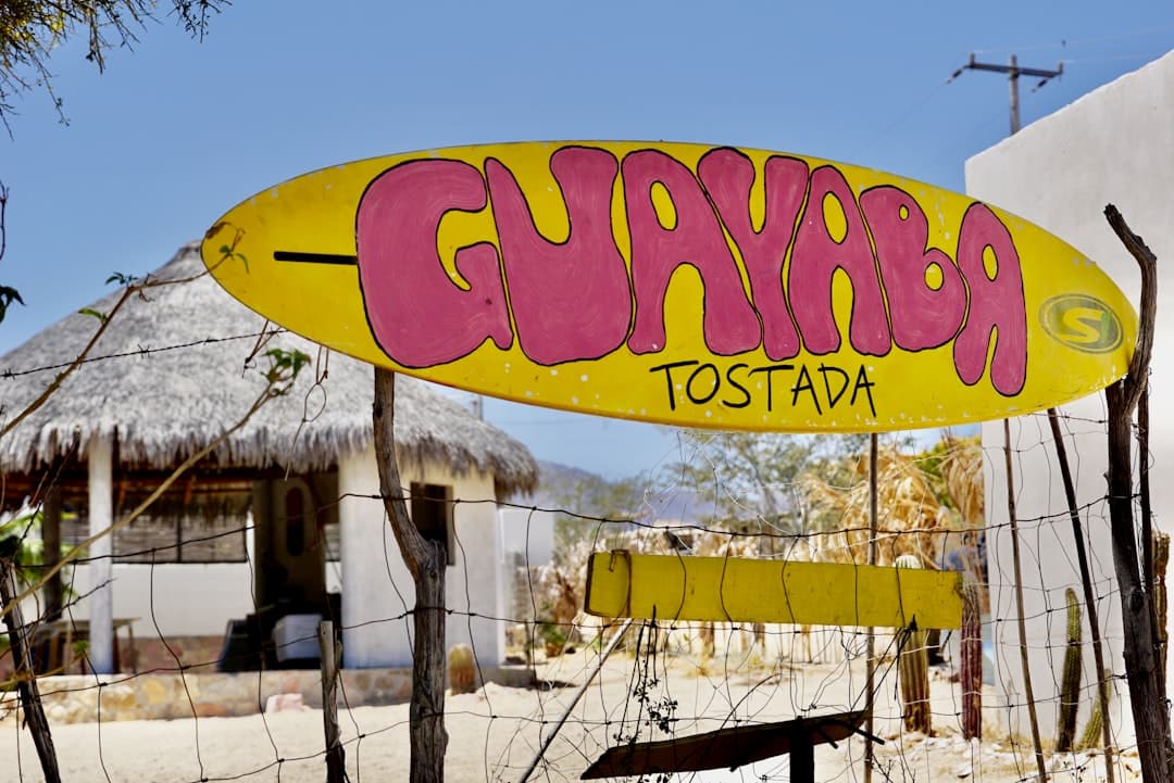 A surfboard sign welcomes guests to a restaurant.