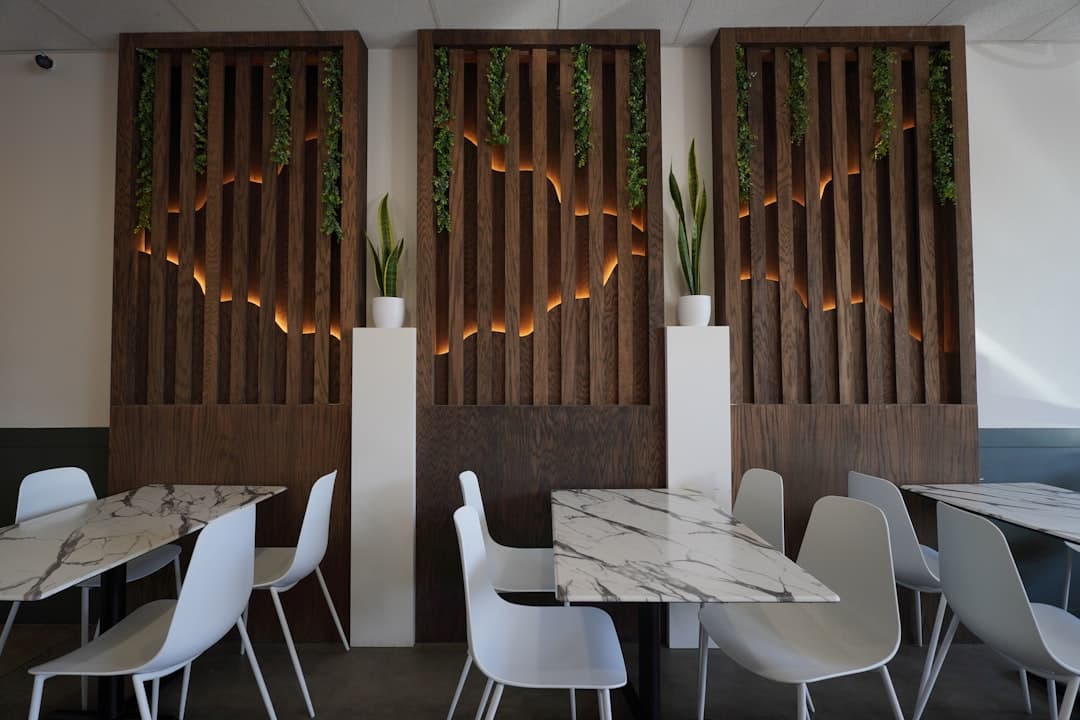 A restaurant with tables and white chairs and wooden screens
