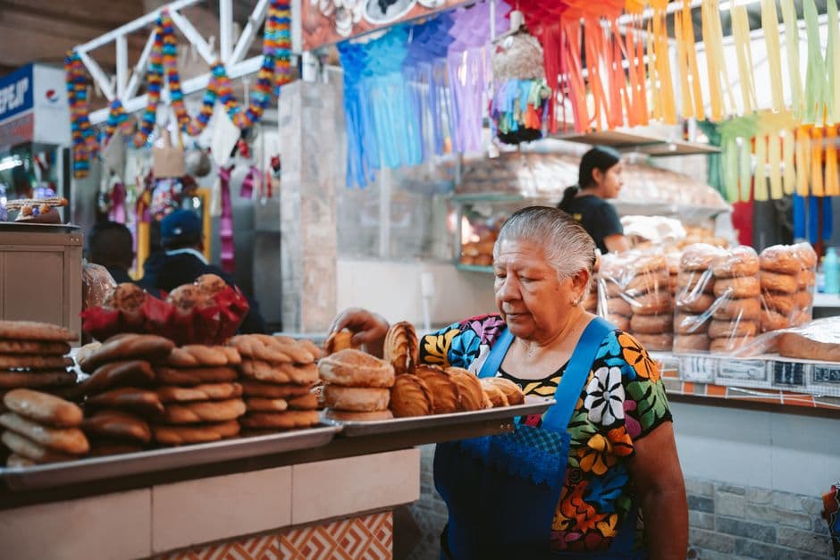 Elderly woman working in a vibrant bakery stall in Oaxaca, Mexico market.