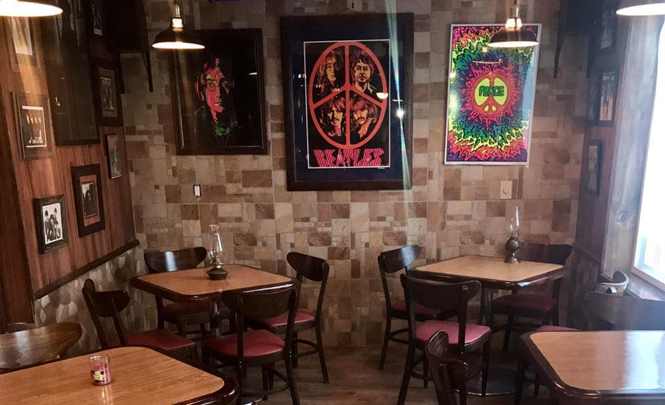 Exterior del Abbey Road Café con su fachada llena de posters de los Beatles y una mesa con la hamburguesa Yellow Submarine — foto de día