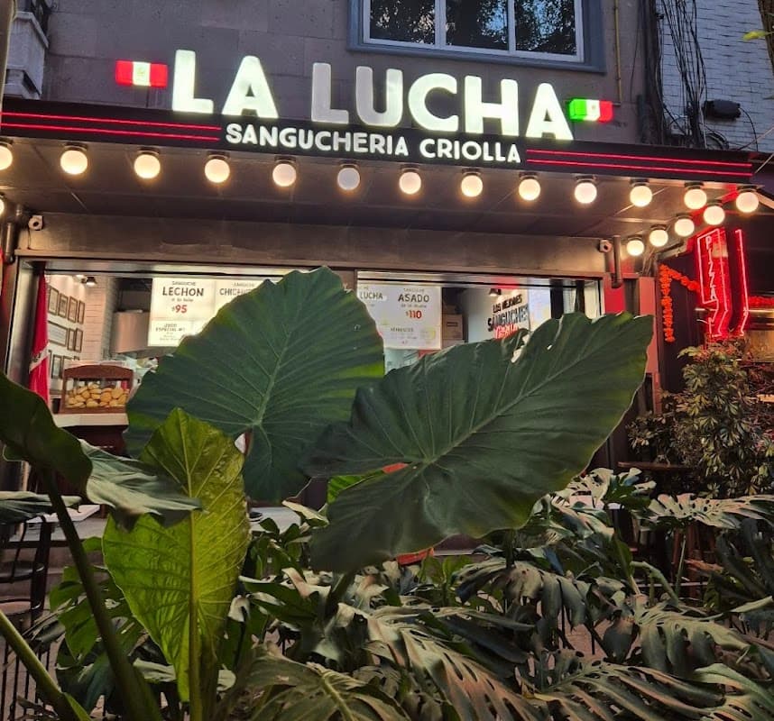 Exterior de La Lucha Sangúcheria Criolla Polanco en Av. Emilio Castelar, con su letrero de neón y la puerta de entrada abierta — vista callejera