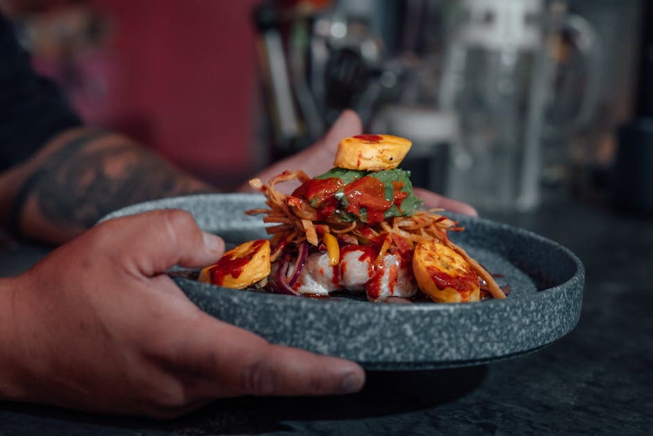 Close-up of a chef's hand holding a gourmet dish in a Ciudad de México restaurant.