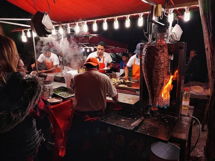 Nighttime street food stall in Mexico City with vendors preparing tacos al pastor.