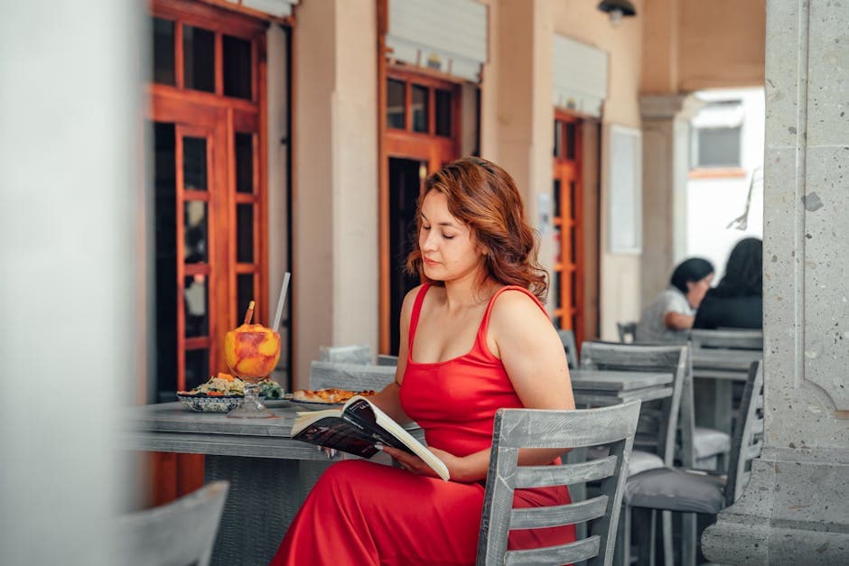 Woman in red dress reads at a cafe in Lerma de Villada, Mexico, with a vibrant atmosphere.