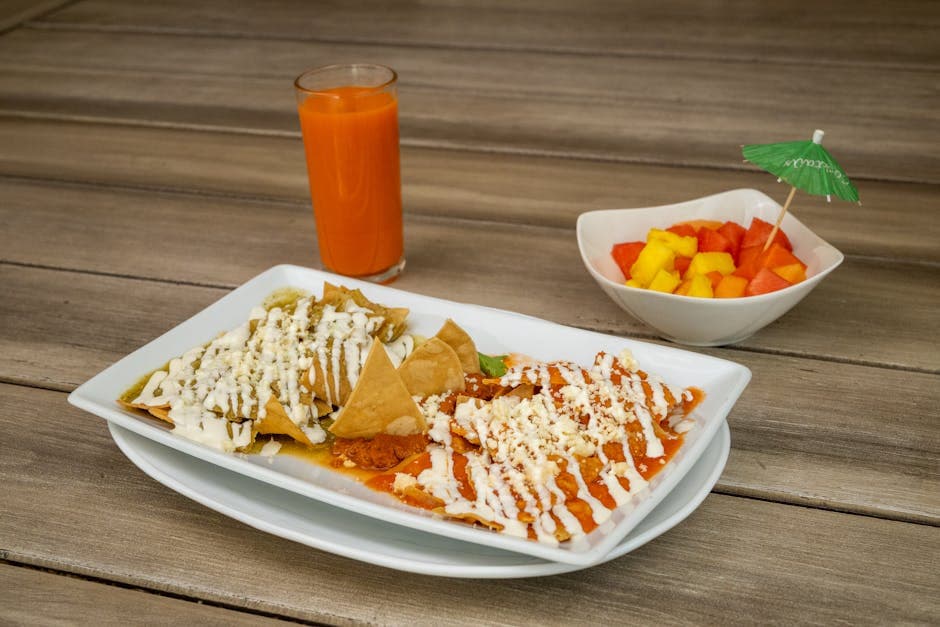 Appetizing Mexican breakfast with chilaquiles, juice, and tropical fruit bowl.