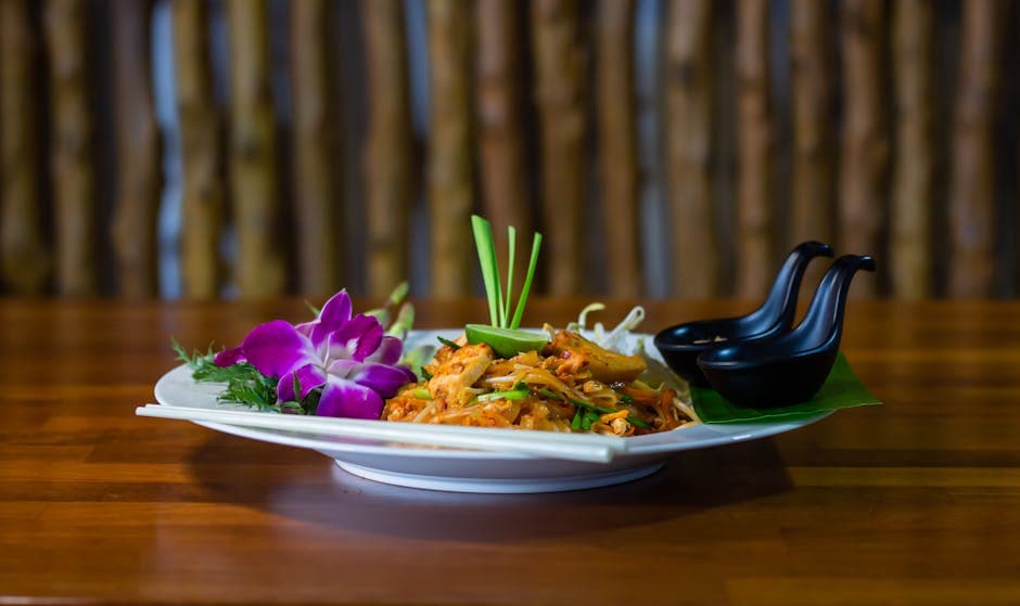 Close-up of a traditional Thai Pad Thai dish with vibrant floral garnishes, exuding a tasty and appetizing look.