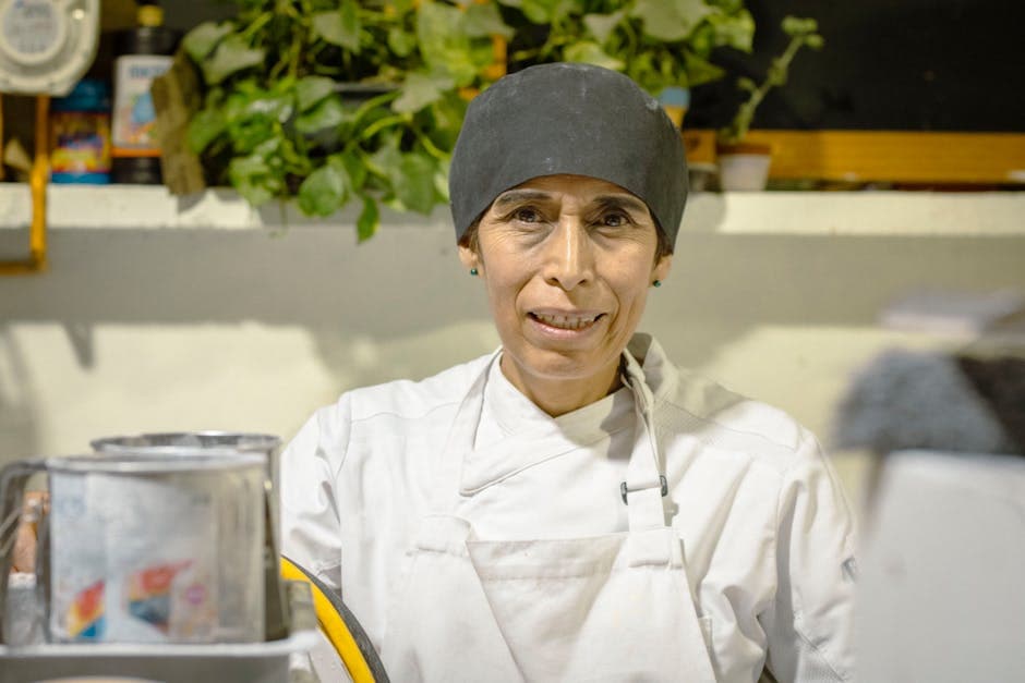 Portrait of a female chef in a Mexico City kitchen wearing apron and hat.