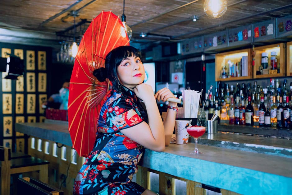 A fashionable woman holding a red umbrella, sitting at a modern bar in Mexico City.