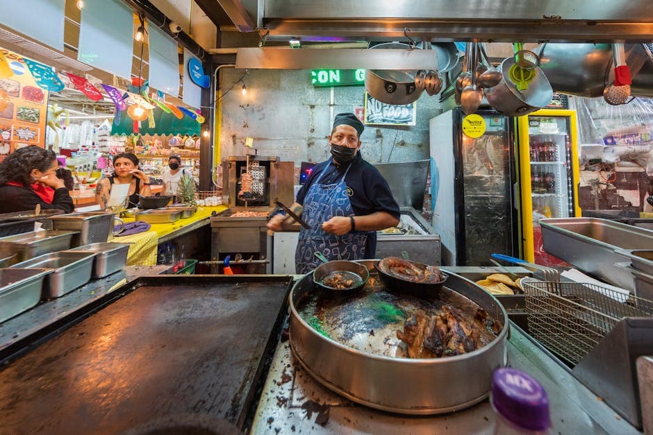Masked vendor cooking street food at a vibrant Mexico City market.