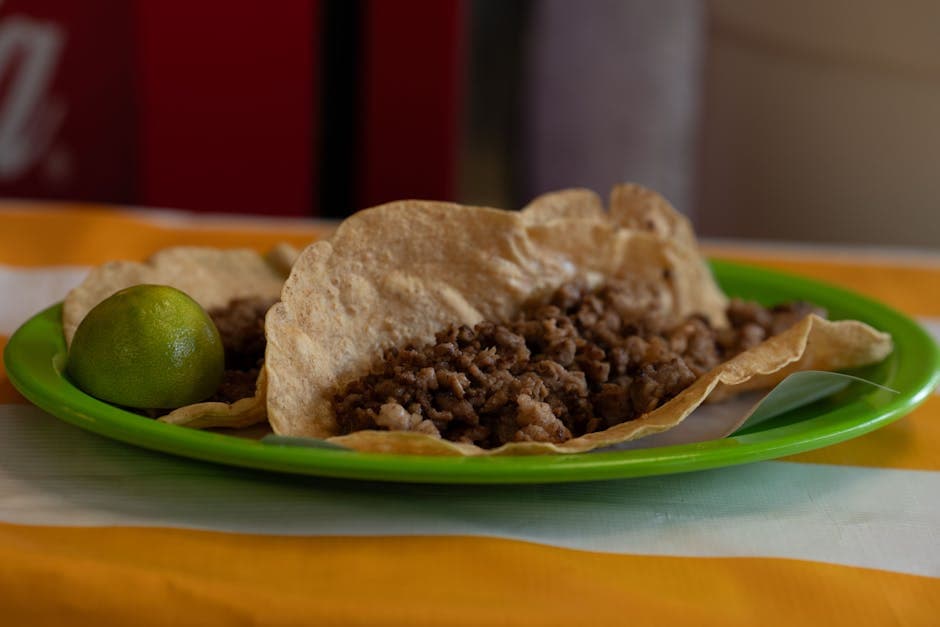 Close-up of traditional Mexican tacos with lime on a colorful plate. Perfect for food photography and culinary themes.