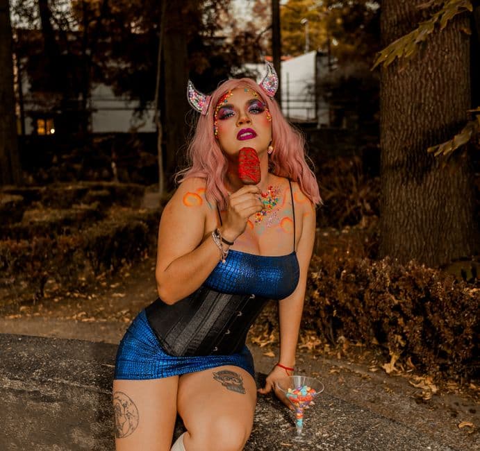 A surreal portrait of a woman with fantasy makeup in a vibrant outfit outdoors.