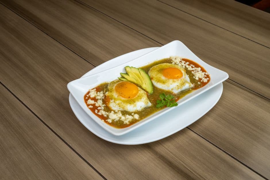 Delicious Huevos Rancheros on a plate with avocado slices in a Mexican restaurant setting.