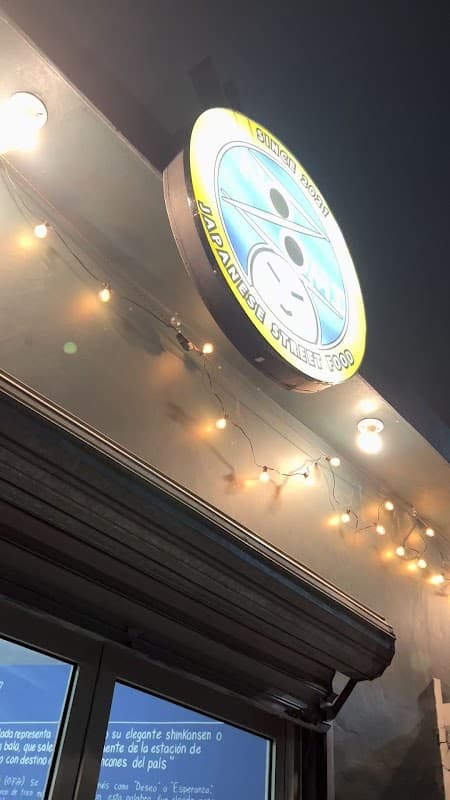 EL TERRENO FOOD PARK — vista panorámica del patio con puestos de tacos y luces de neón al anochecer