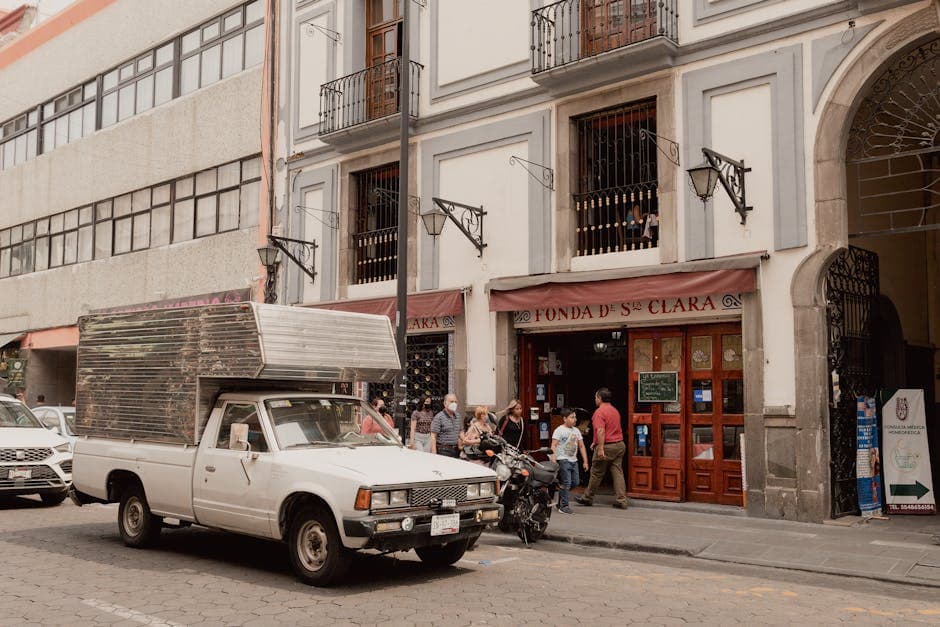 A lively street scene in Heroica Puebla de Zaragoza featuring people and a vintage truck.