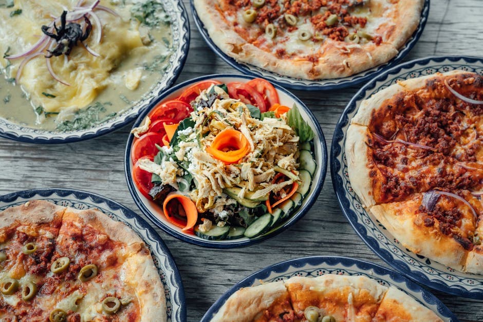 Top view of mixed Mexican pizza and salad dishes, showcasing vibrant colors.