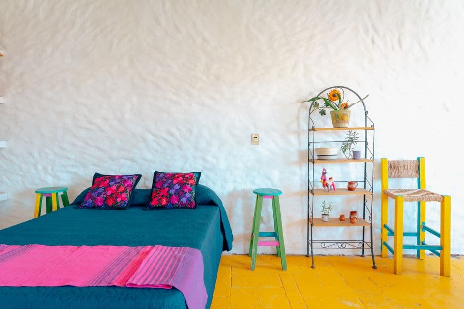 A bright and colorful home interior featuring a vibrant bed and eclectic furniture arrangement.