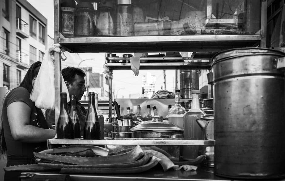 Candid black and white photo of a street food vendor in Trujillo, capturing local culinary culture.