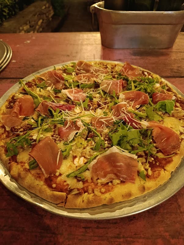 Interior de Dinonni Pizza Mesón italiano con horno de leña y una pizza recién salida del horno