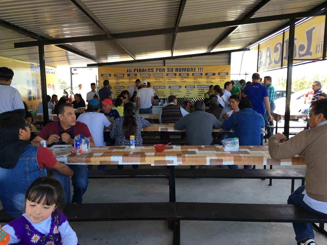 Fachada de Tacos Lucas en Blvd. Aeropuerto, con letrero rojo y clientes en fila bajo la luz de la mañana