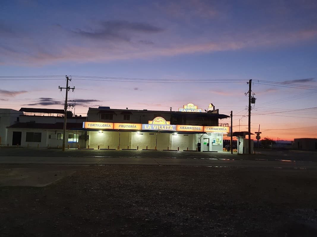 Exterior iluminado de Restaurant Pancho con su letrero de neón y una mesa de tacos sobre la barra — vista nocturna