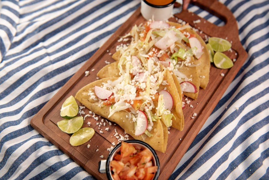 Delicious Mexican tacos served on a wooden platter with fresh limes and toppings. Perfect food photography for culinary blogs.